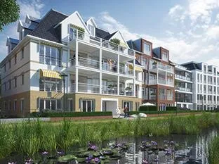 Lejlighedskomplekset Residence Vijverpark i Overveen i klassisk arkitektonisk stil med altaner og en dam i forgrunden.